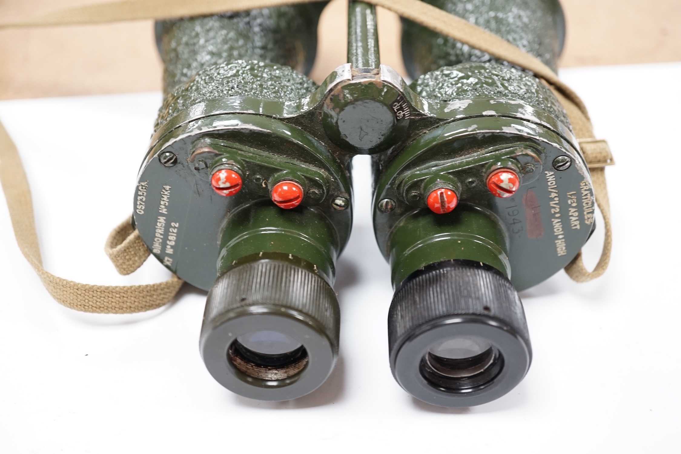 A pair of leather cased, green painted military Binoprism No.5 Mk.4 binoculars, dated 1943, the lid of the leather case impressed with; ‘ 1945 OS/997 Binocular Prismatic No.5 case Mk.1.’ Condition - fair to good, some an